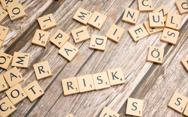 Scrabble tiles on a table with the word RISK front and centre